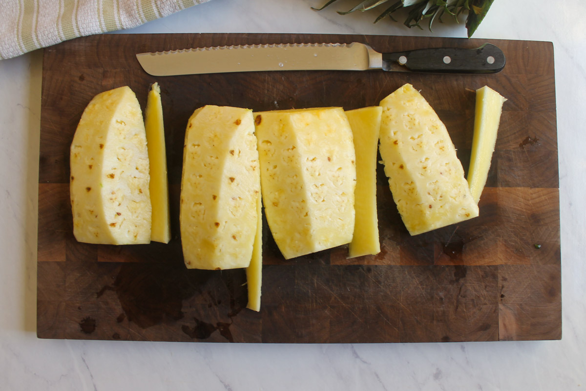 Cutting a pineapple into quarters and removing the core.