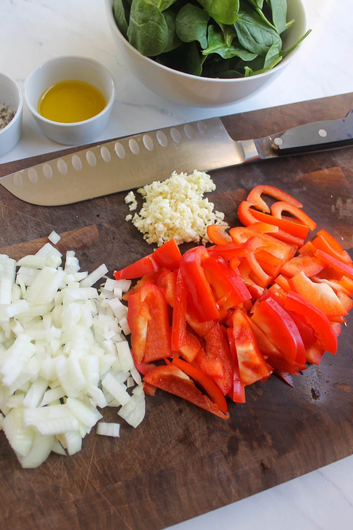 Prepared ingredients on a cutting board, chopped onions, red bell pepper, and minced garlic.