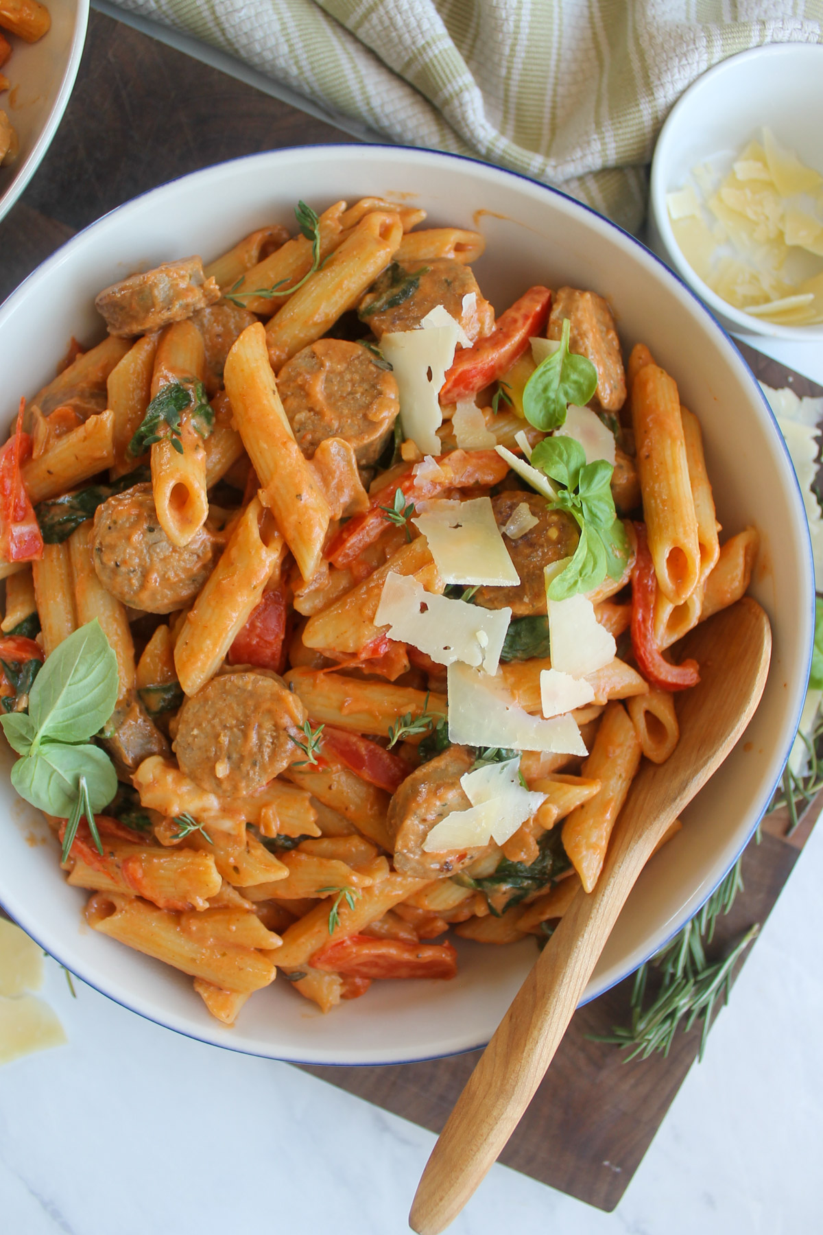 A finished bowl of creamy tomato pink sauce pasta with sausage and fresh Italian herbs.