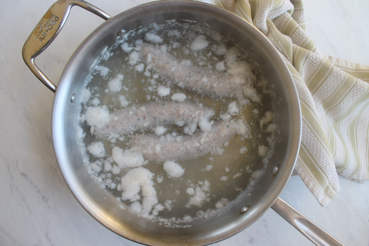 Simmering the Italian sausage in water to cook through.