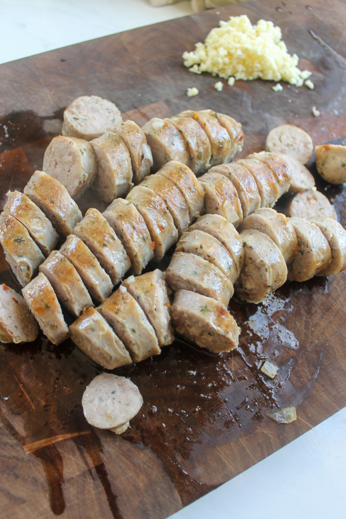 Sliced Italian sausage links on a cutting board.