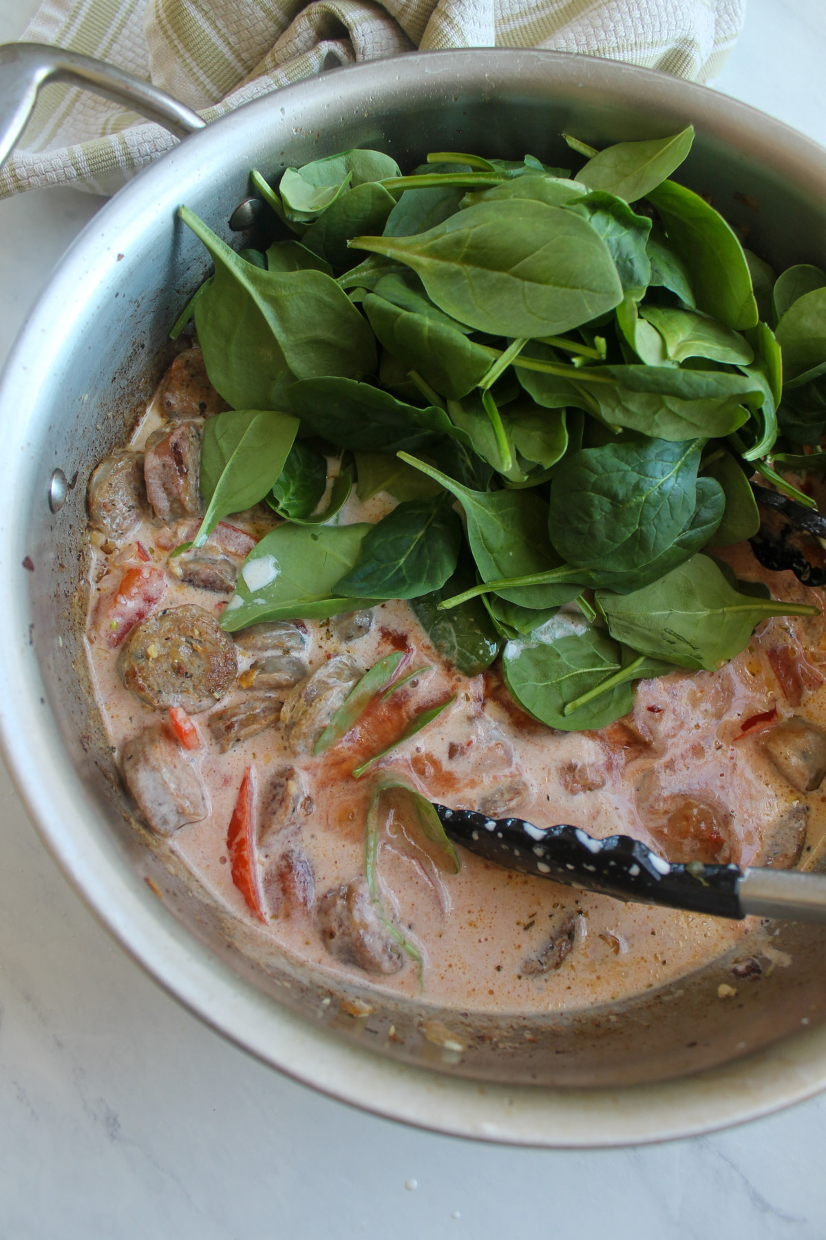 Making the creamy pink sauce by adding canned tomato sauce and half & half with fresh spinach.