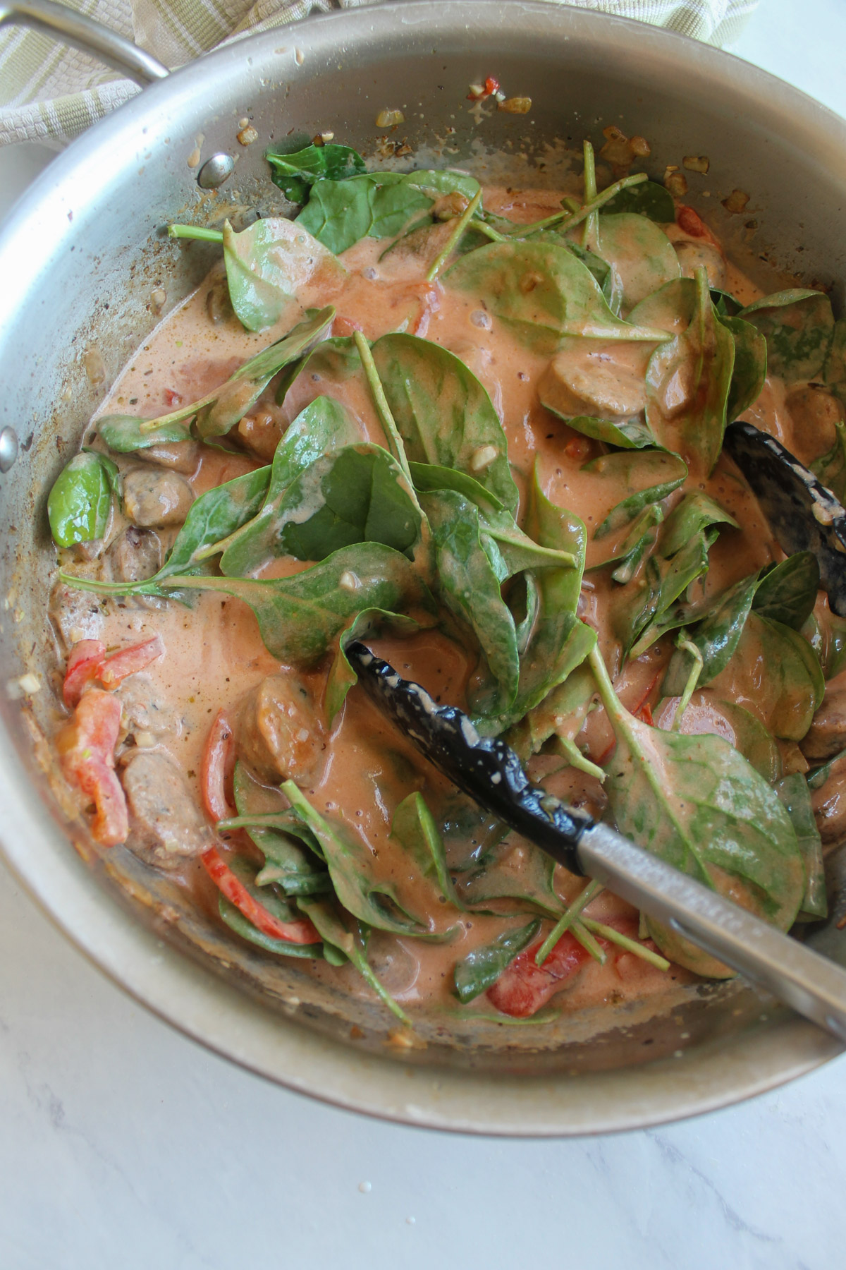 Mixing the creamy tomato pink sauce with the raw spinach and begin to simmer.
