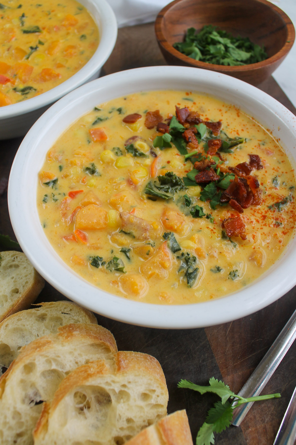 A bowl of sweet potato corn soup topped with bacon and cilantro.