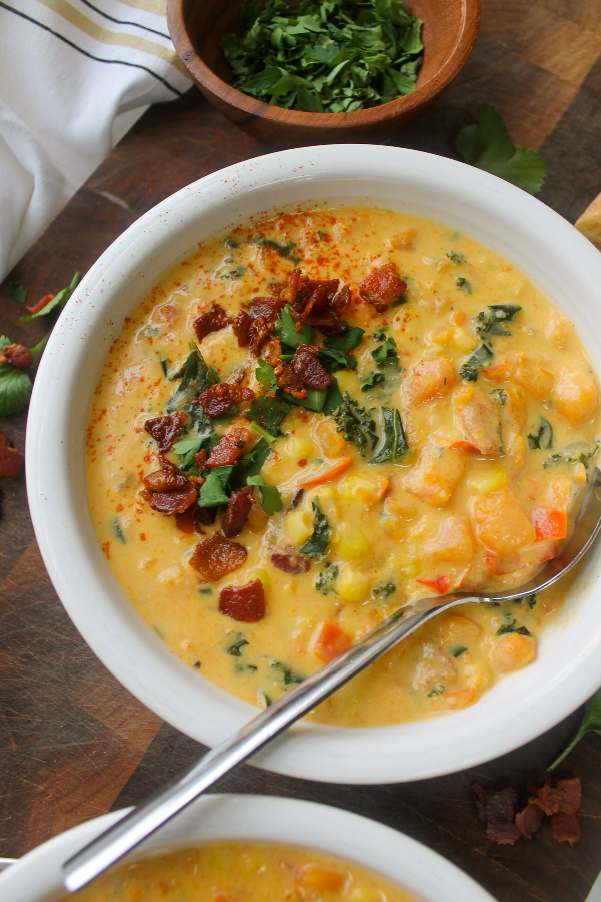 Bowls of sweet potato corn chowder with kale and crispy bacon.