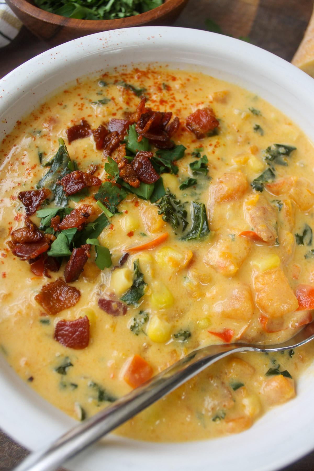 Close up of a bowl of sweet potato corn chowder soup with a spoon.