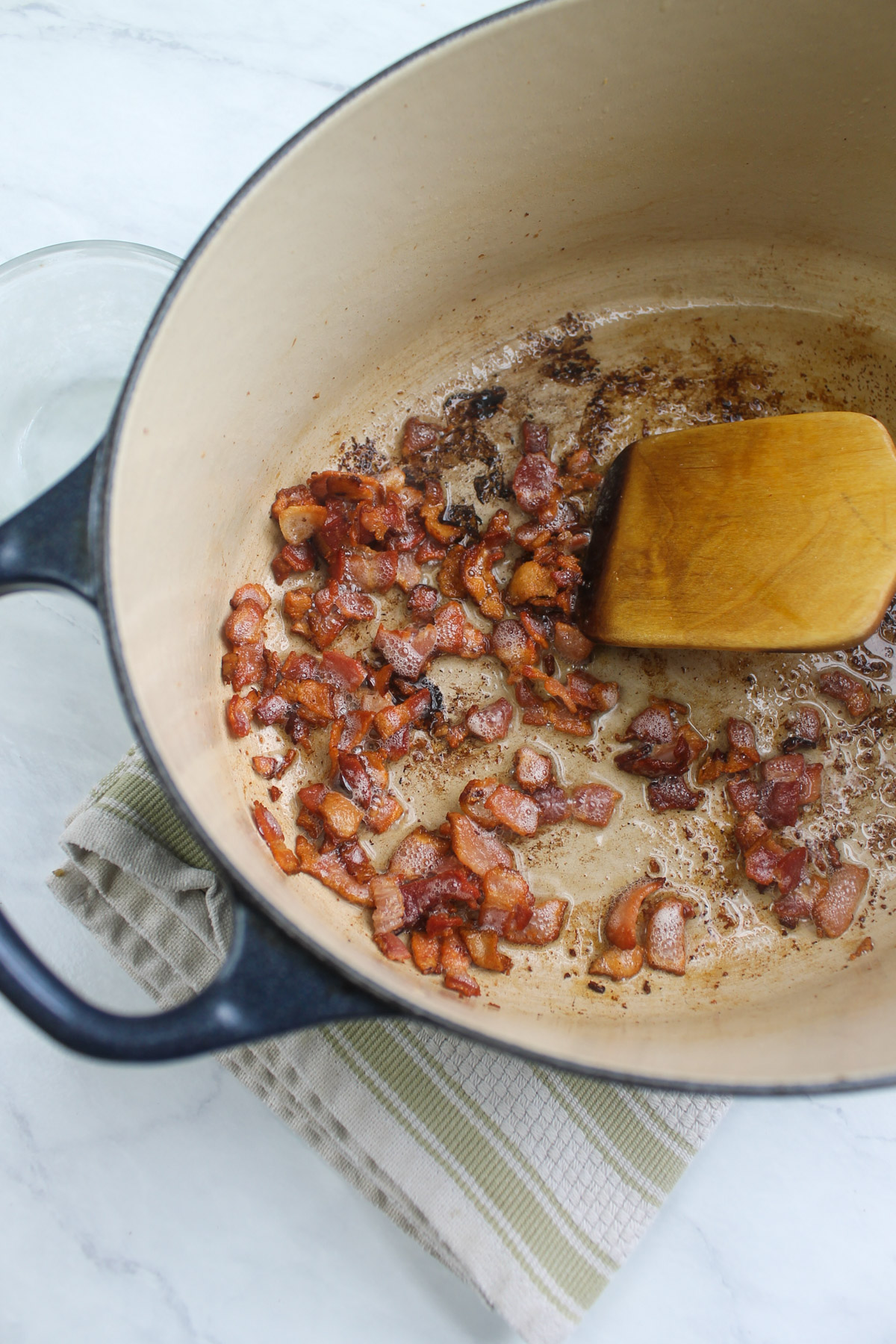 Cooking chopped bacon in a Dutch oven soup pot.