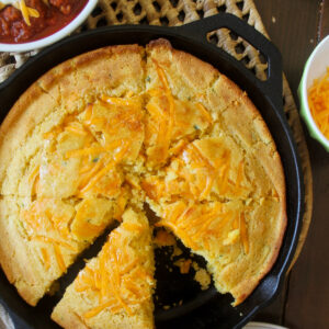 Honey cheddar cornbread with zucchini and bell pepper in a cast iron skillet.