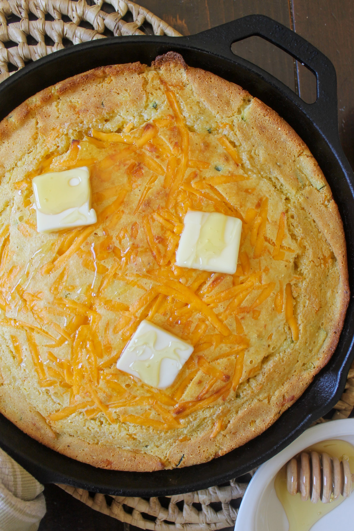 Skillet Cornbread topped with melted cheddar cheese, butter and drizzled with honey.
