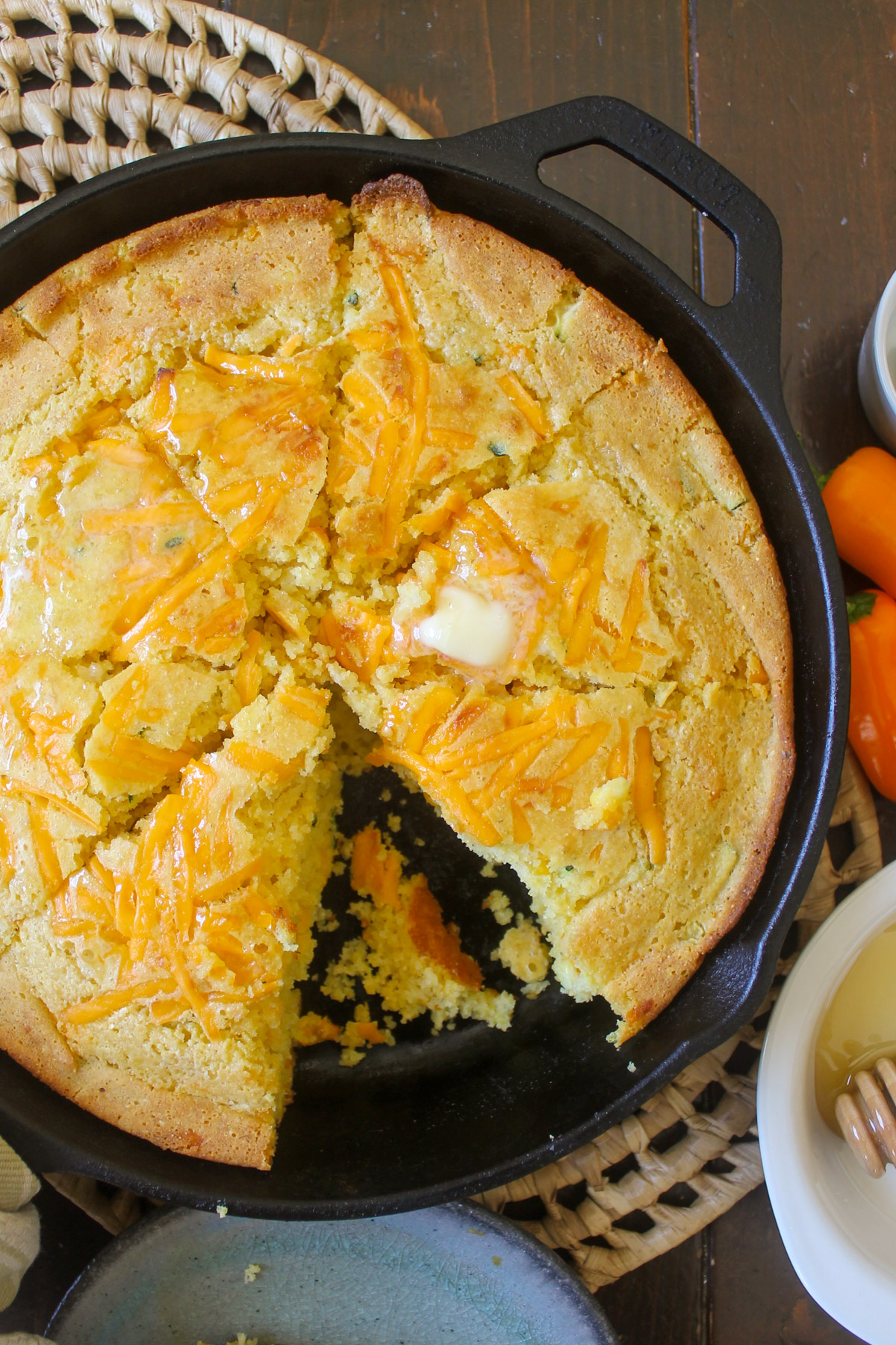 Honey cheddar cornbread sliced in a cast iron skillet.