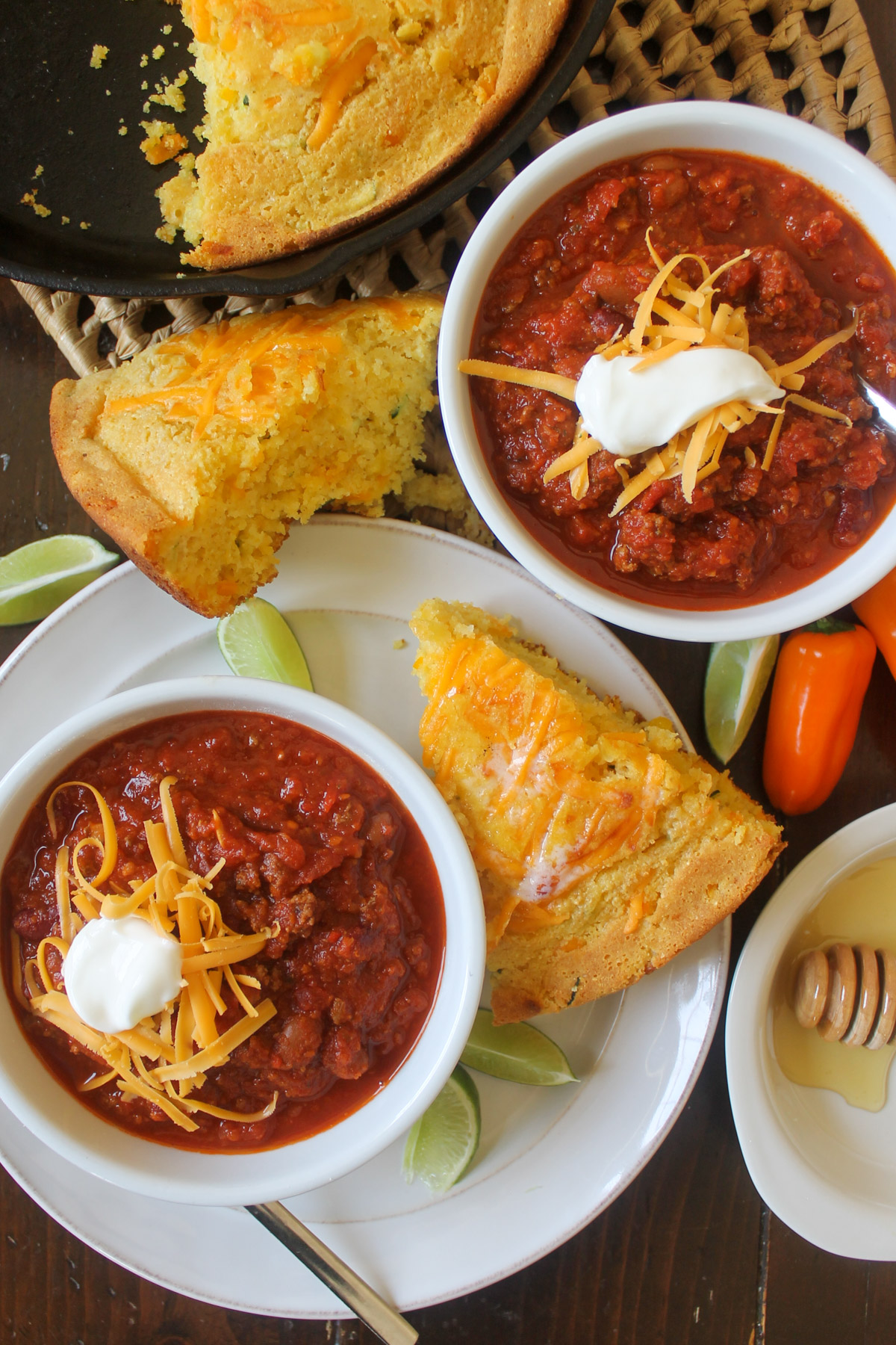 Two bowls of chili served with honey glazed cornbread wedges.