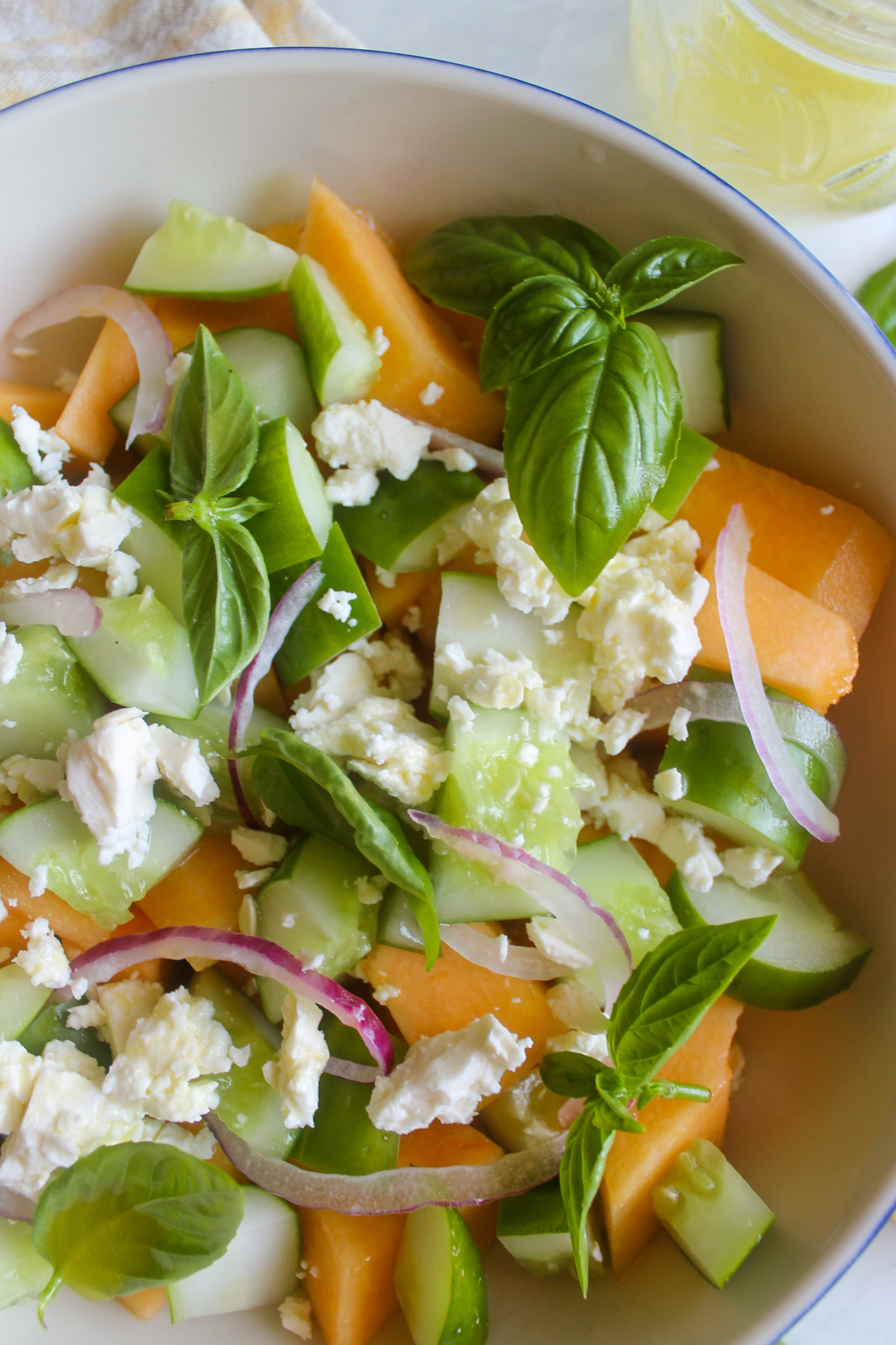 Cucumber Melon Salad in a bowl with vinaigrette dressing.