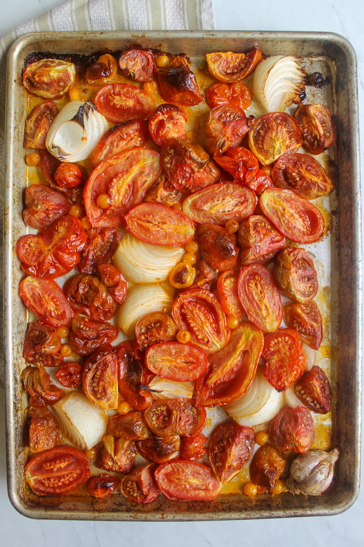 A sheet pan of roasted tomatoes, onions, and garlic for tomato soup.