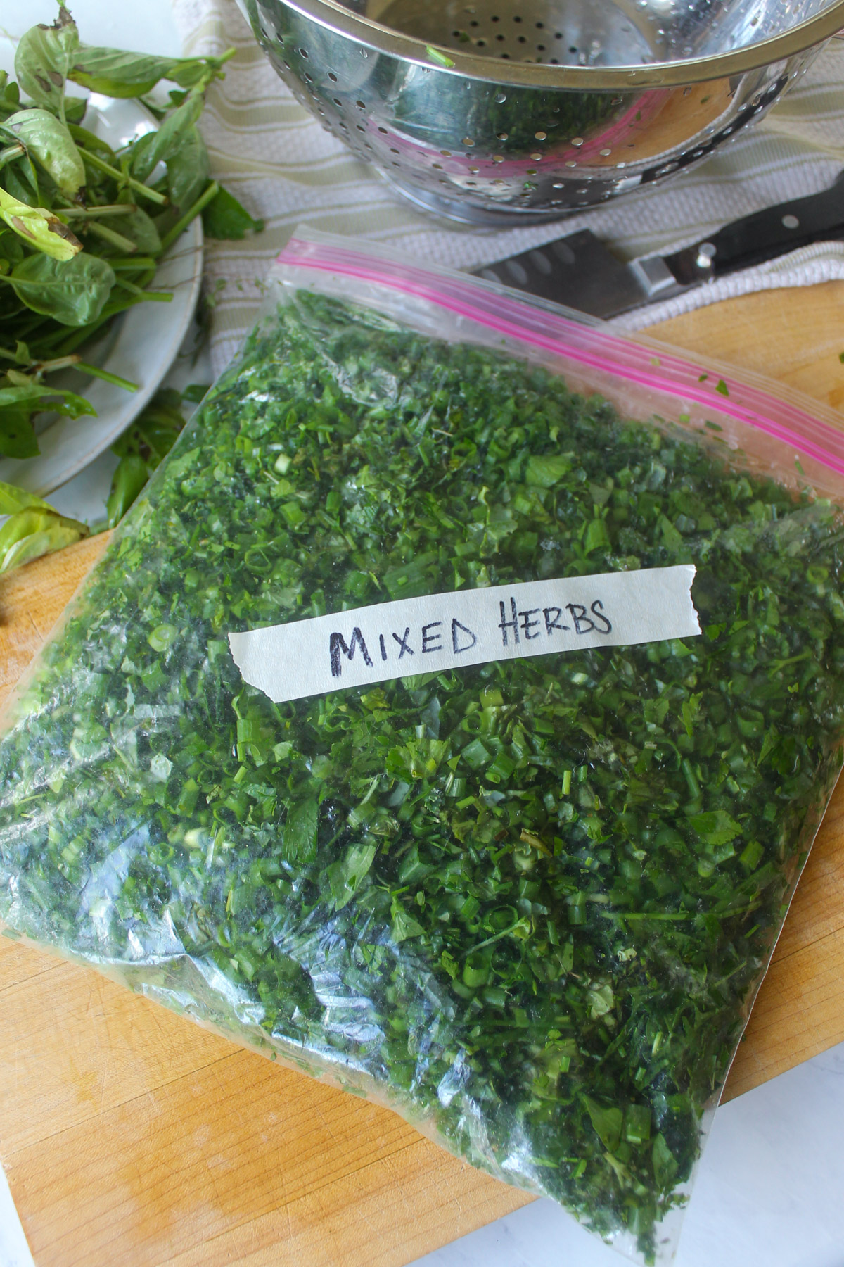 A freezer bag of mixed herbs and greens with a label taped on it Mixed Herbs.