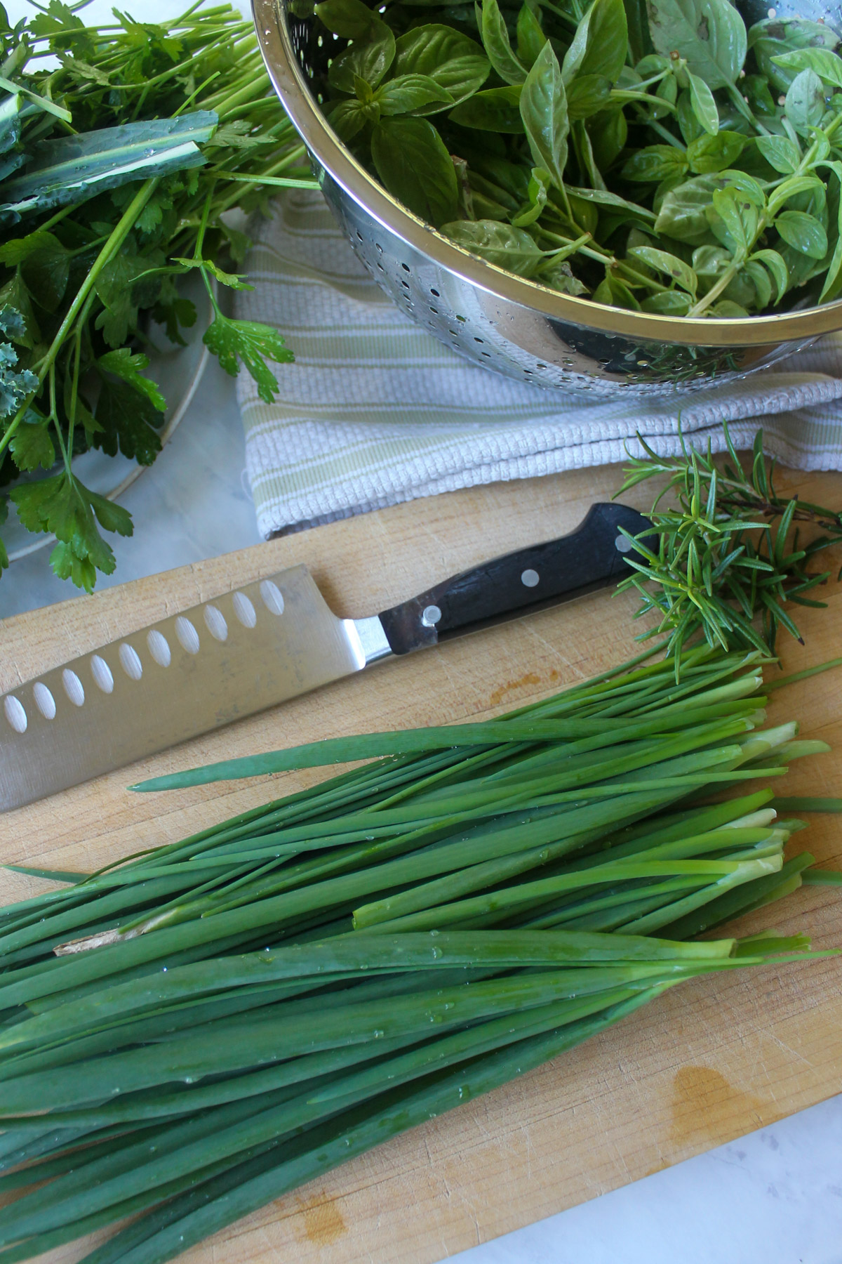 Scallions and chives on a cutting board ready to chop and freeze.