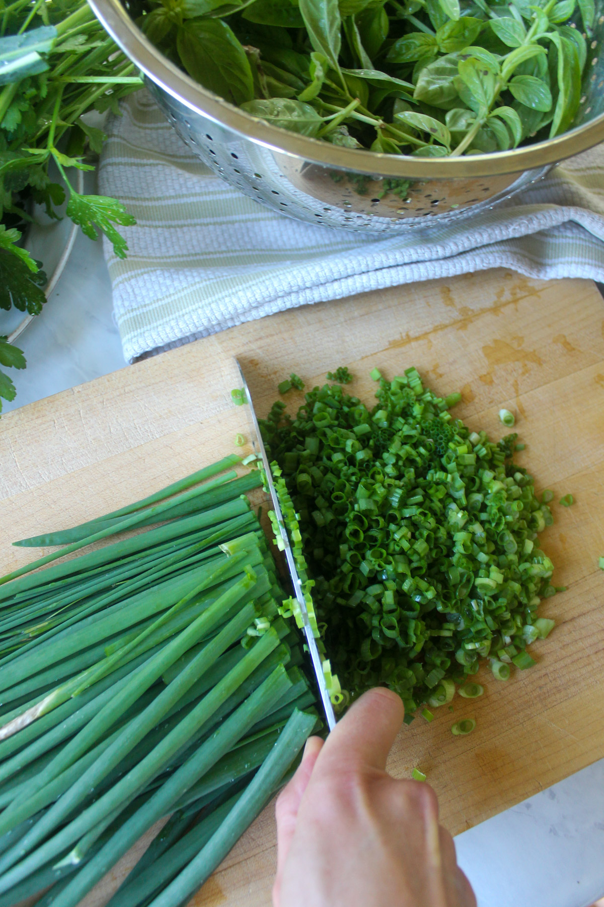 Chopping scallions and chives on a cutting board.