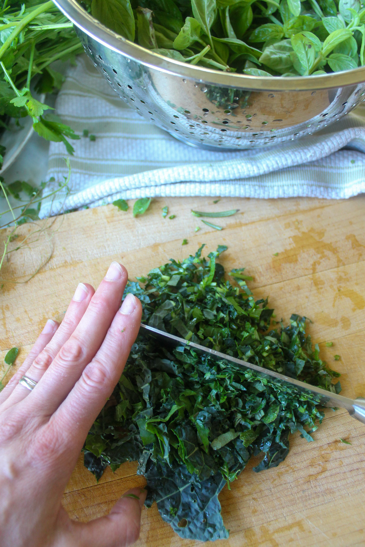Chopping greens and herbs on a wooden cutting board.