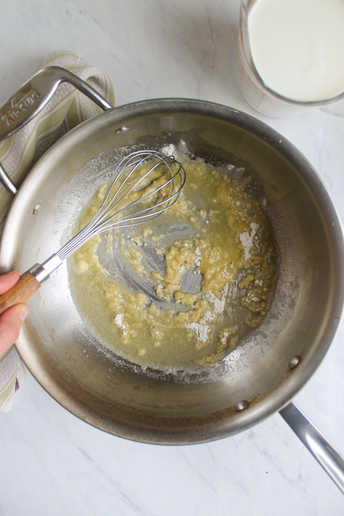 Whisking butter and flour together to form a roux, the thickener for broccoli au gratin sauce.