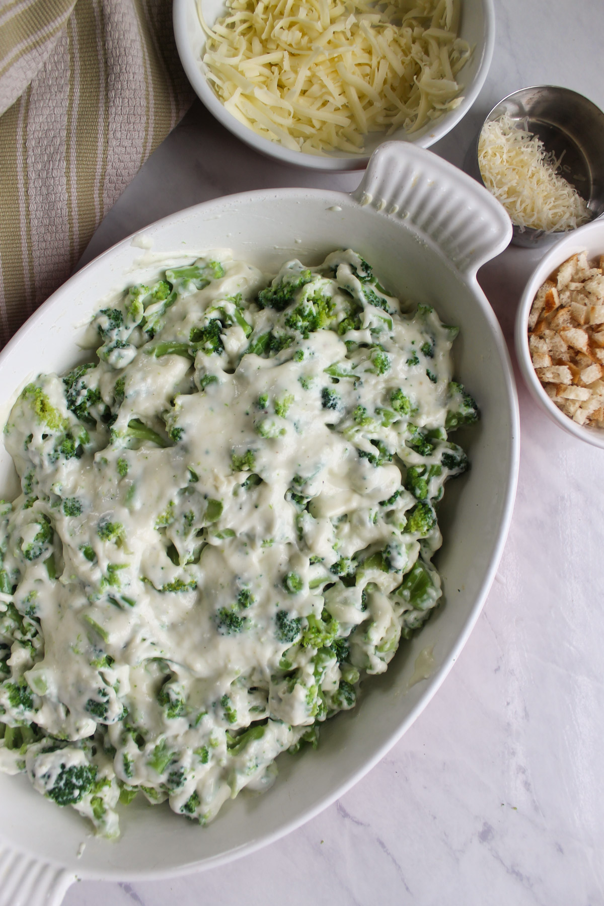 Frozen broccoli mixed with a white cheesy bechamel sauce in a baking dish.