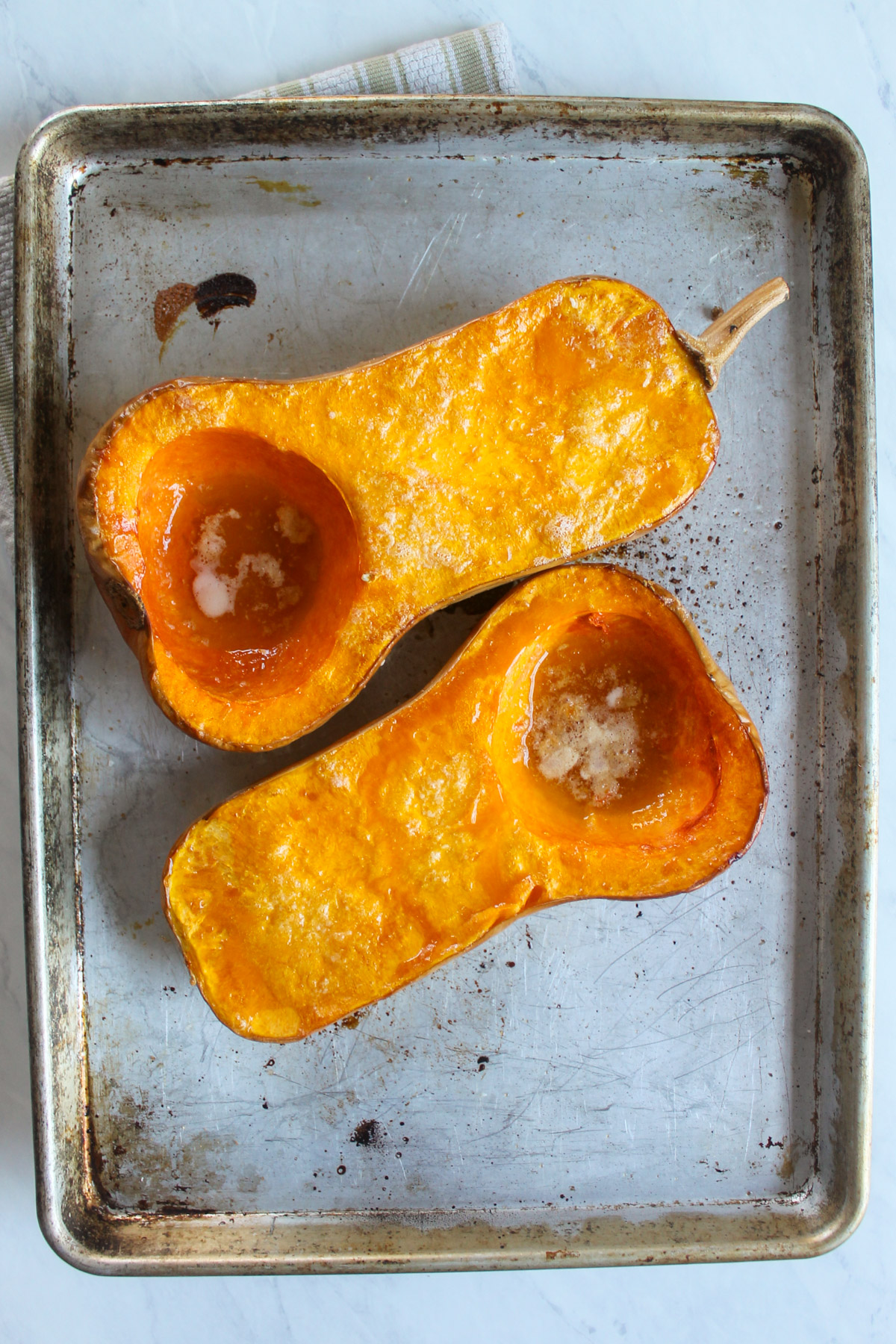 Two roasted butternut squash halves on a sheet pan.