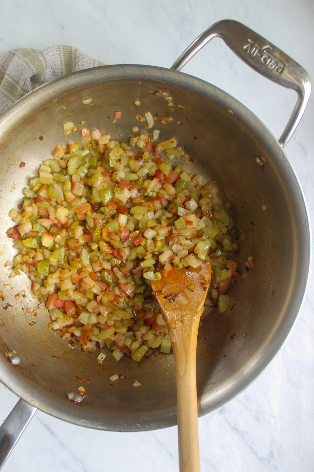 Onion, celery, and apple cooking in a skillet.