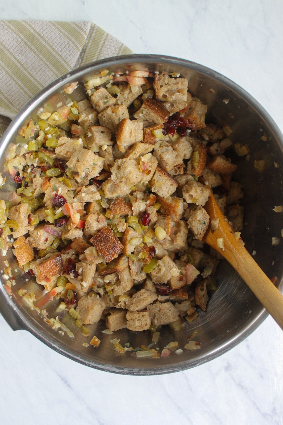 A large mixing bowl with the bread cubes, sauteed onions, celery and apple and egg mixture.