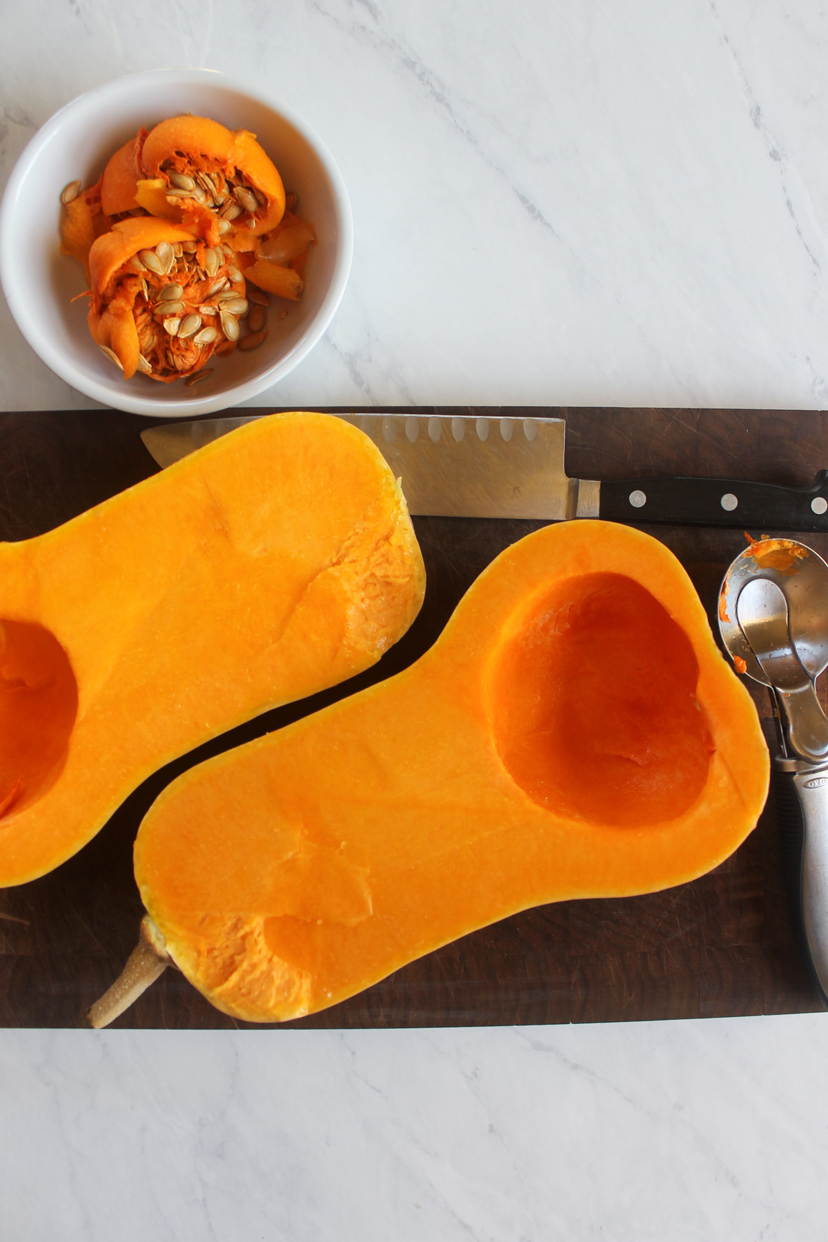 A butternut squash cut open in half with the seed cavity removed.