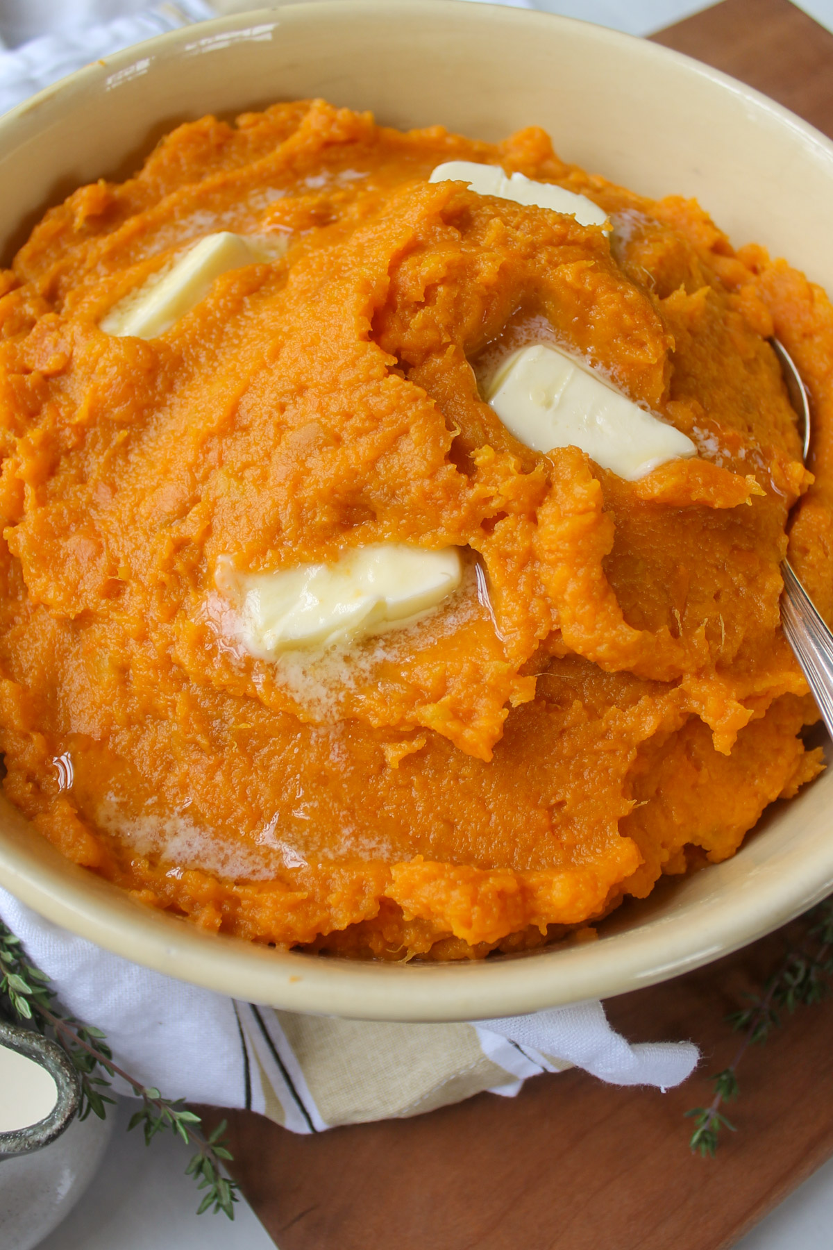 A yellow bowl of mashed sweet potatoes with butter.