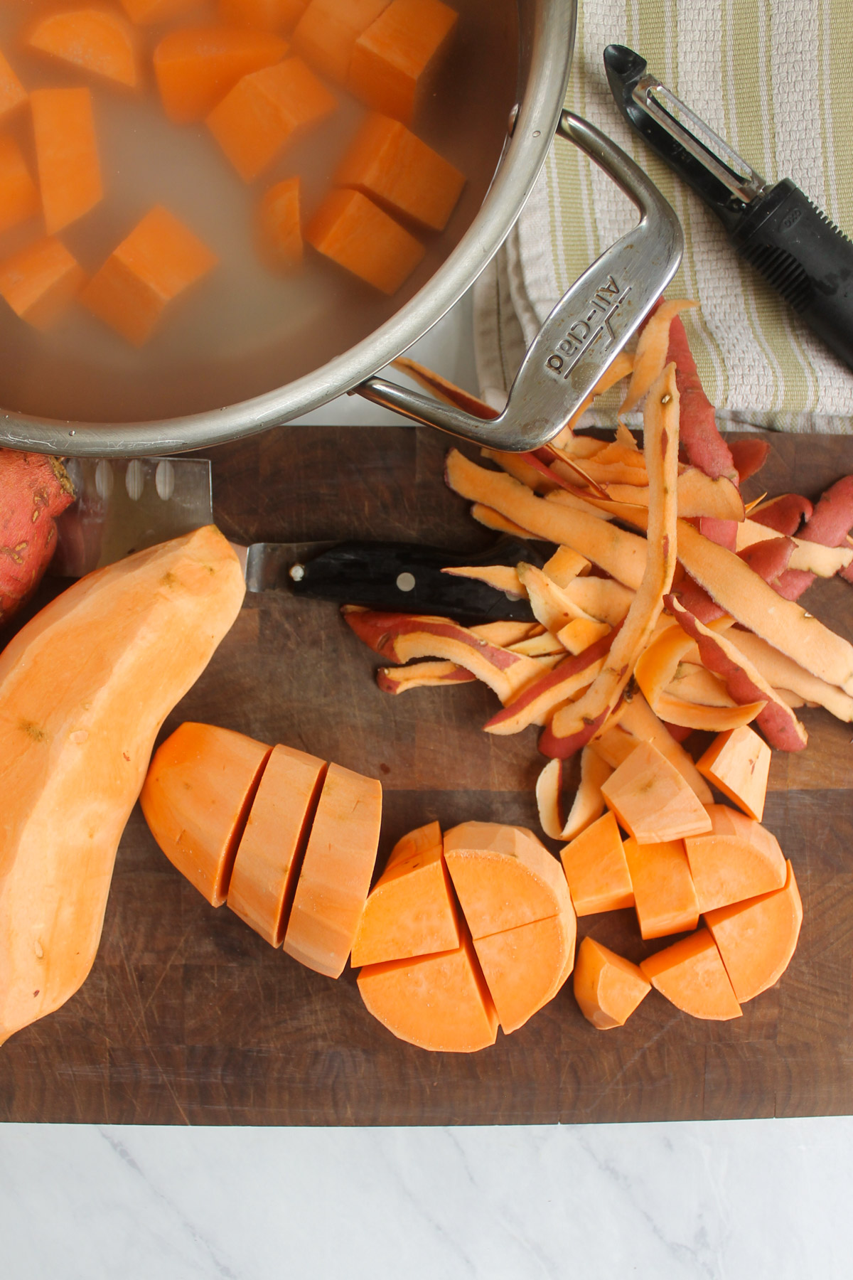 Sweet potatoes peeled and chopped on a cutting board.