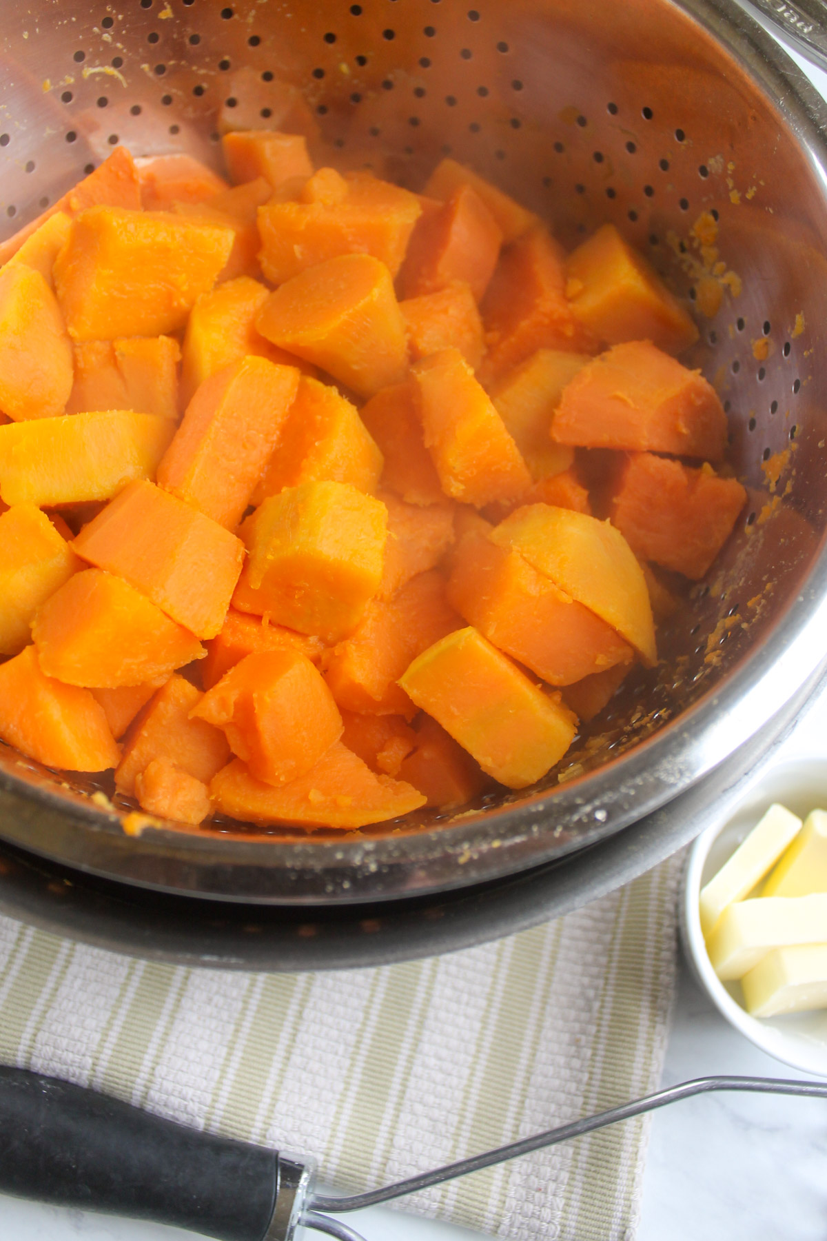 Boiled sweet potato chunks drained in a colander.