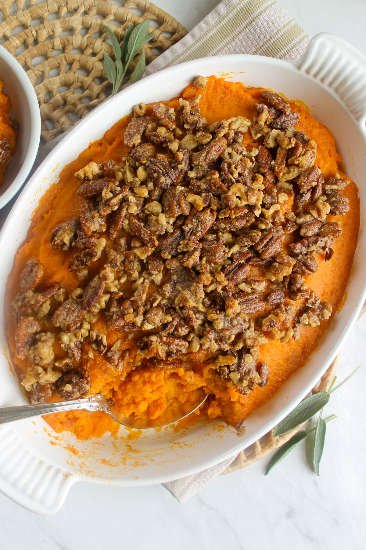 Sweet potato casserole with maple pecan topping in a white baking dish.