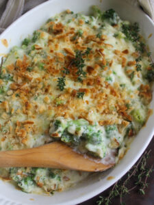A baking dish of broccoli au gratin with white cheddar and browned breadcrumbs.
