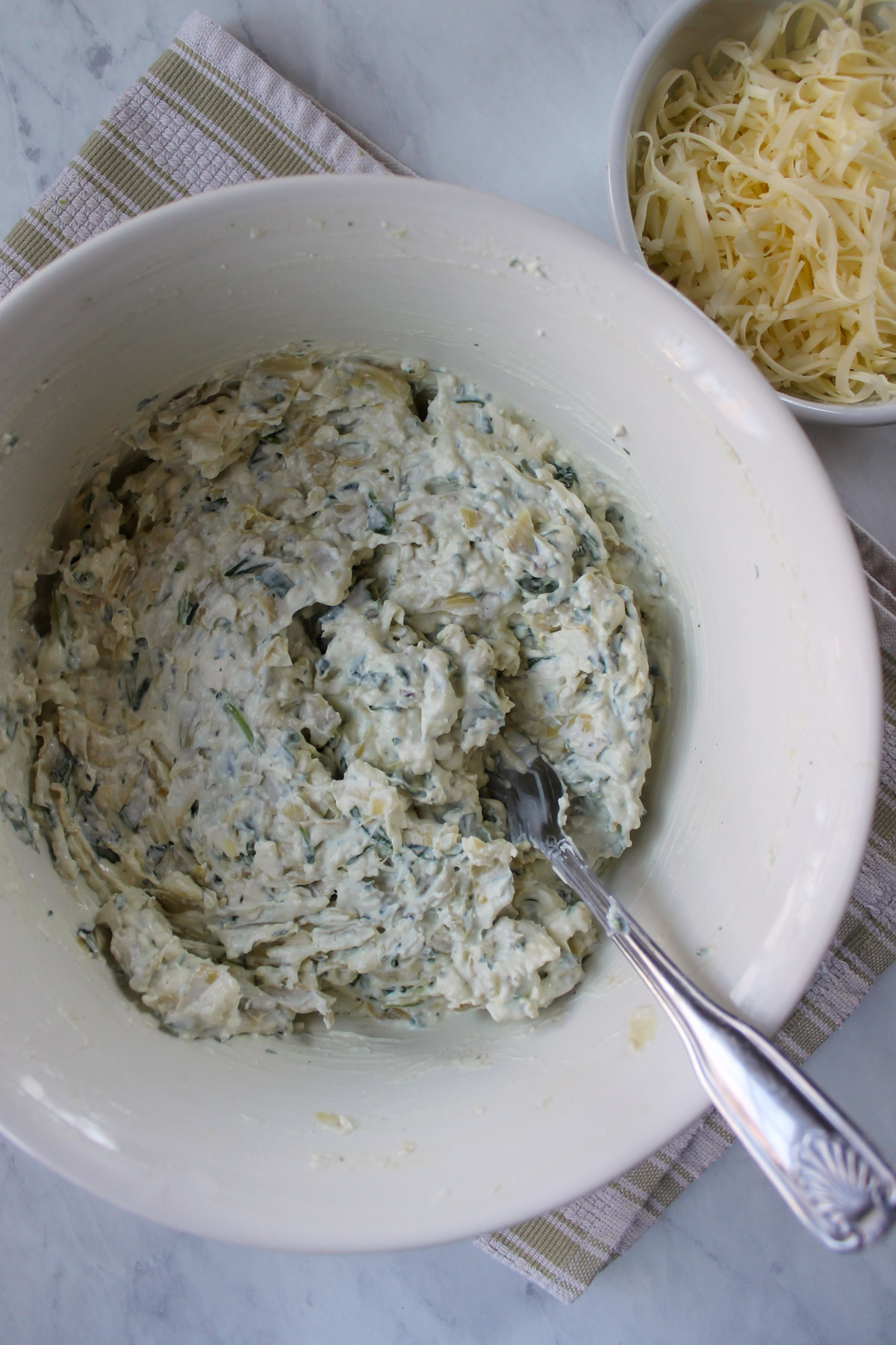 Goat cheese artichoke dip ingredients mixed together in a bowl.