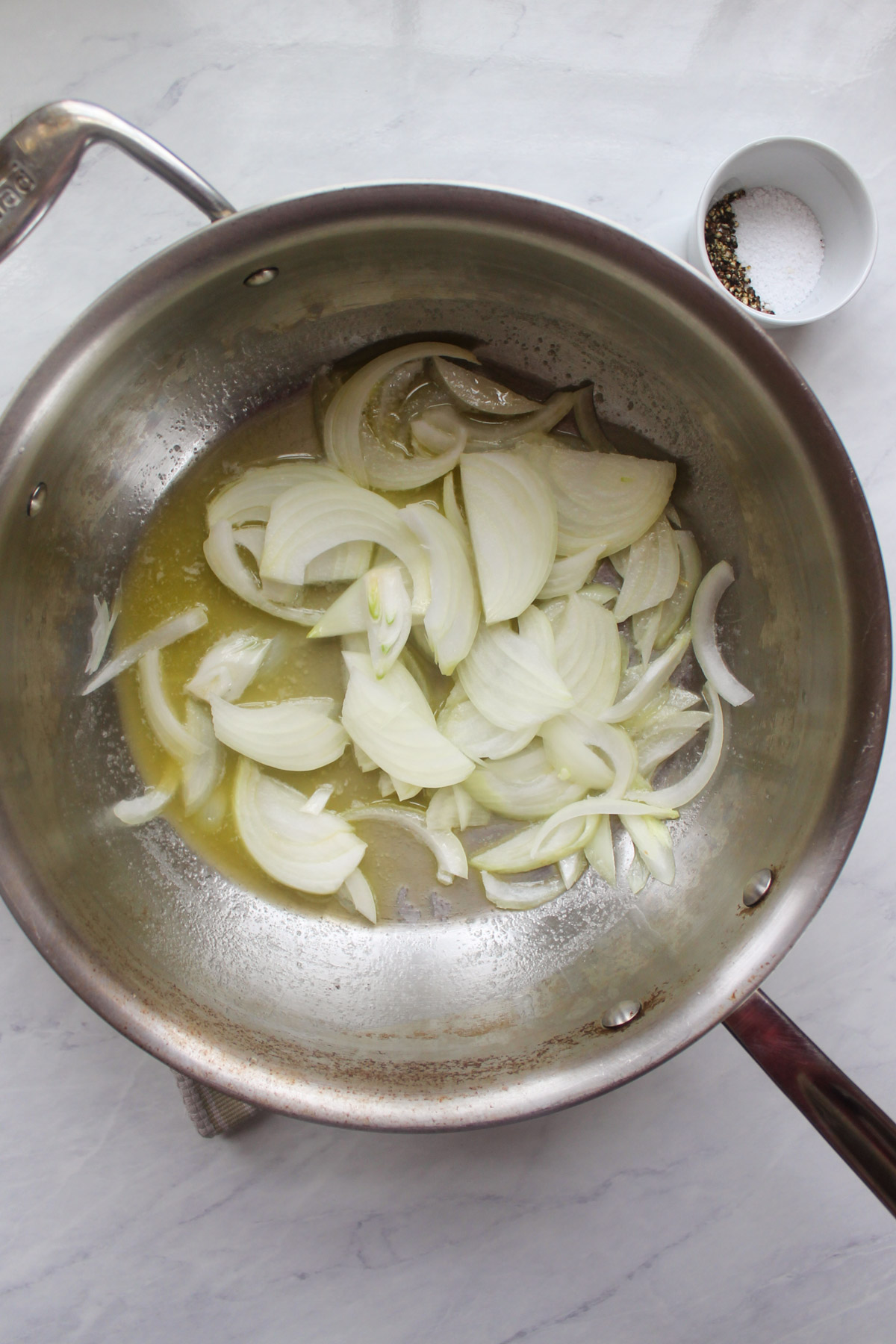 Sliced onions added to a skillet with melted butter.