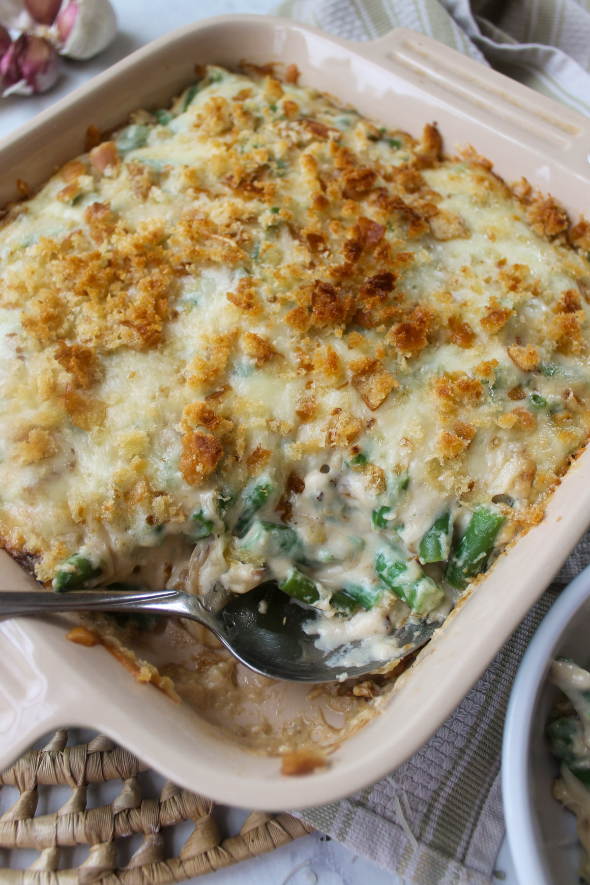 A casserole dish of baked green bean au gratin with toasty bread crumbs.