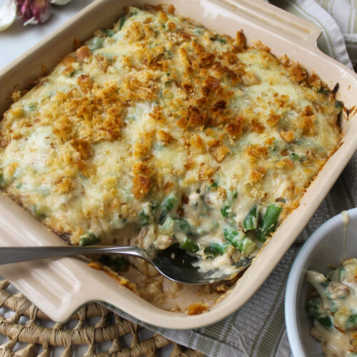 A baking dish of green bean au gratin with white melted cheese.