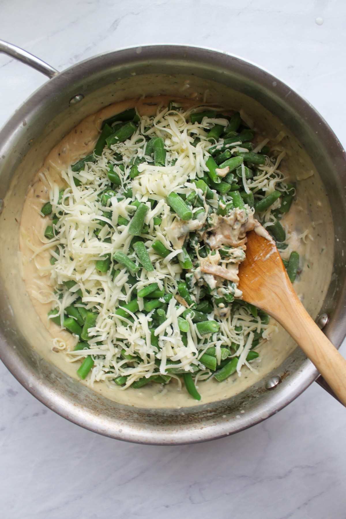 The frozen green beans and shredded cheese added to the creamy sauce.