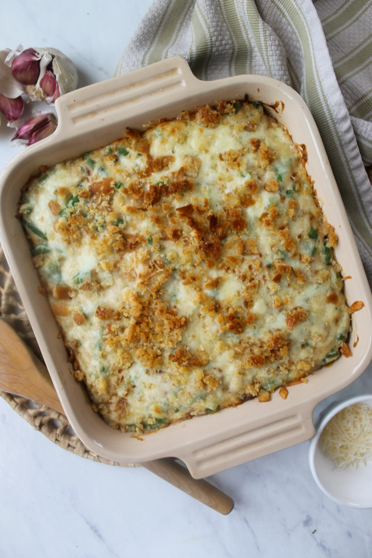 Bubbly golden baked green bean au gratin in a square casserole dish.