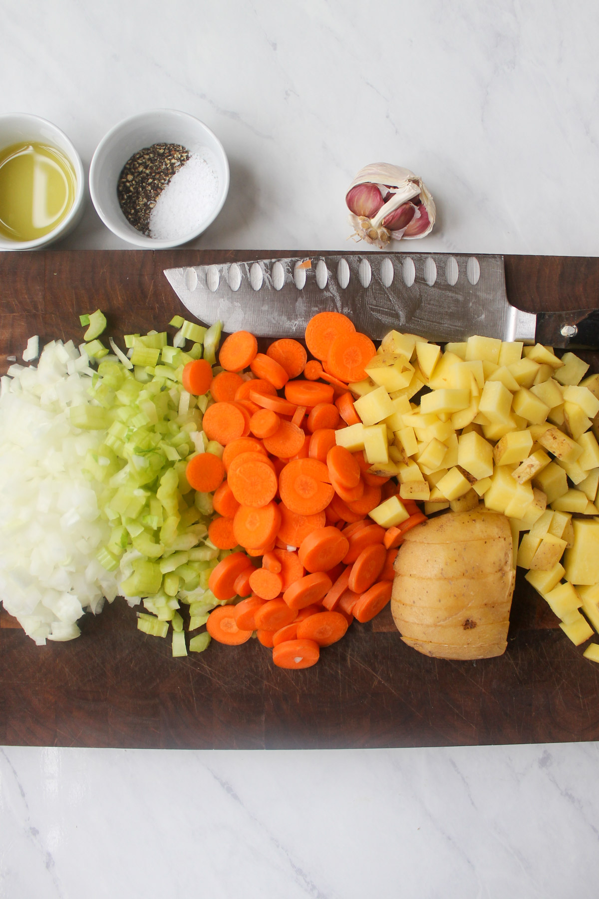 Chopped vegetables on a cutting board, onion, celery, carrots and potato.