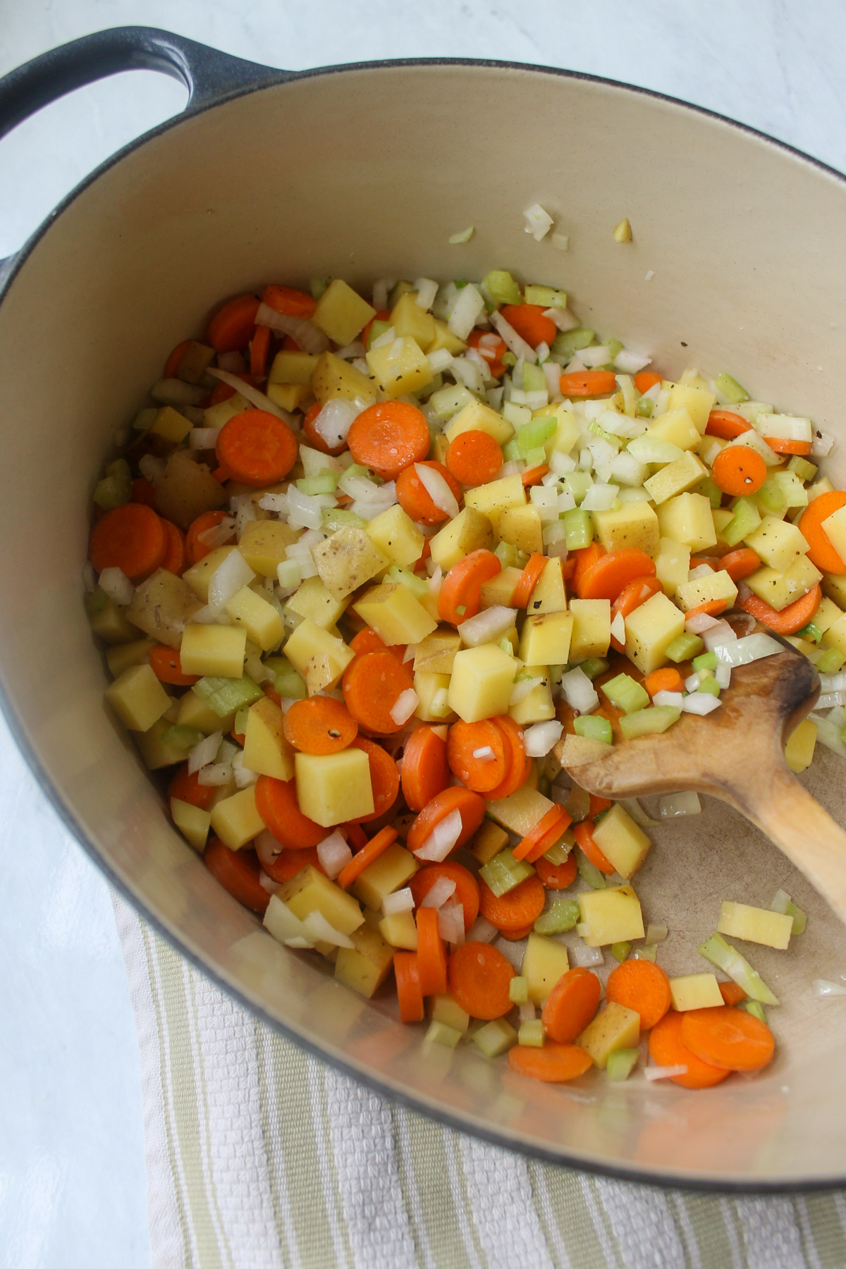 Sautéing onion, celery, carrot and potato in a soup pot.