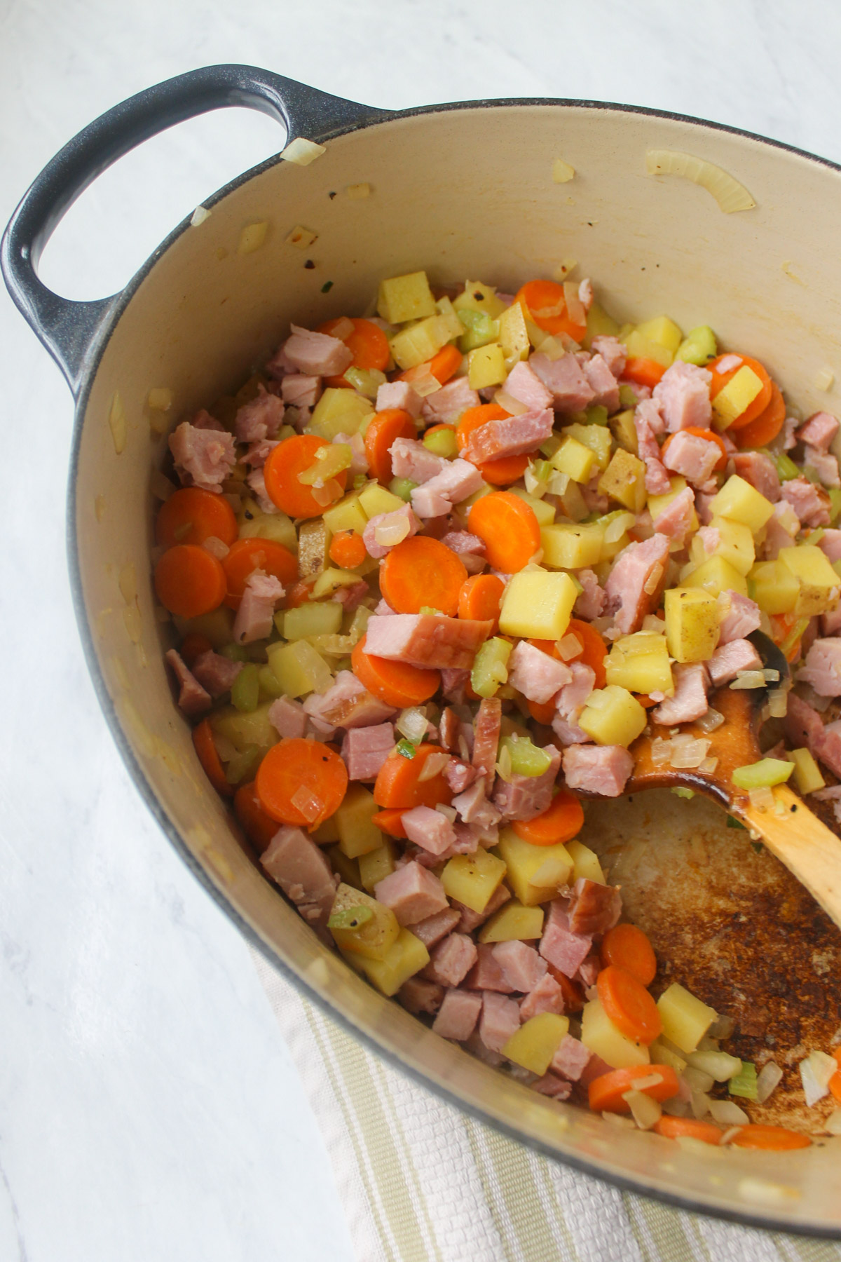 Diced ham added to a soup pot with onions, celery, carrots and potato.