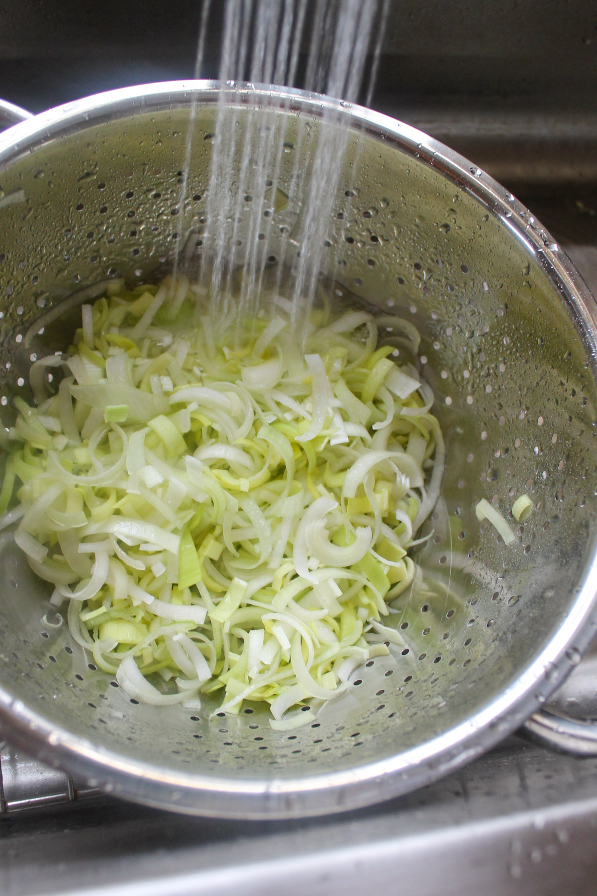 Spraying the leeks in a colander.