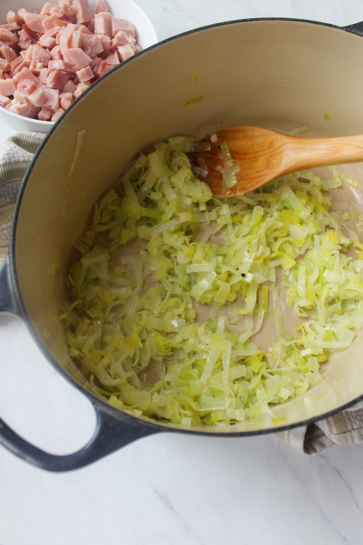 Sautéing leeks in butter in a soup pot with a wooden spoon.
