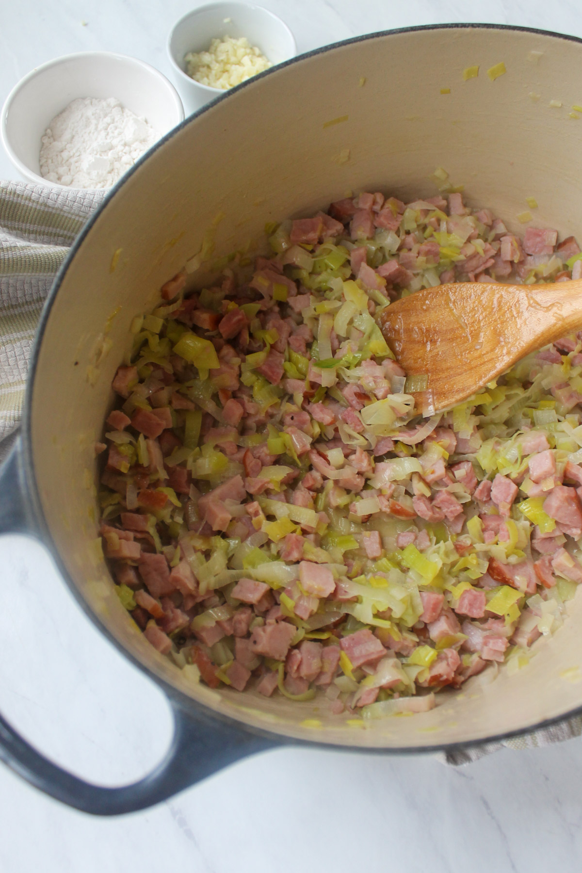 Sautéing leeks with chopped ham.