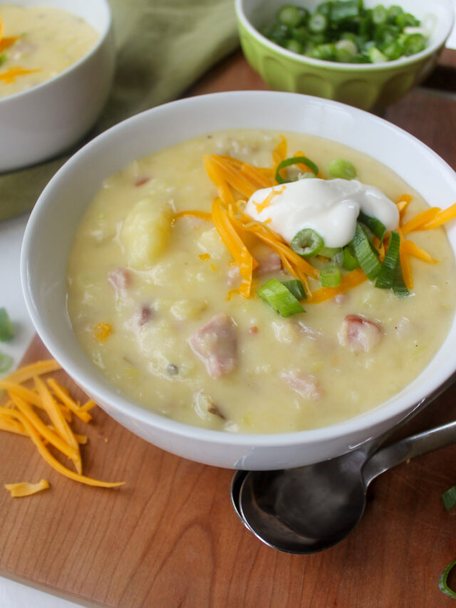 A bowl of creamy Potato Ham & Leek Soup with toppings.