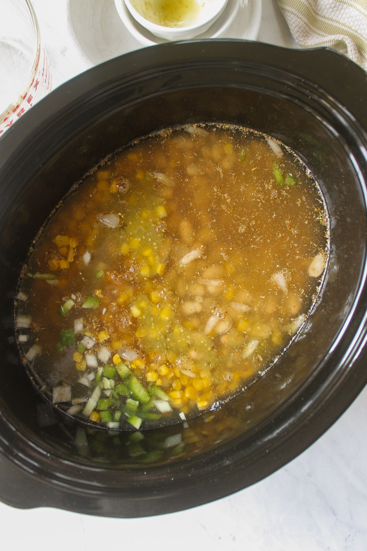 All ingredients for white chicken chili added to a slow cooker.