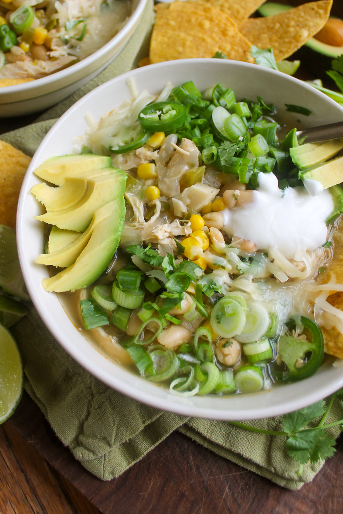 White chicken chili in a bowl with lots of green toppings.