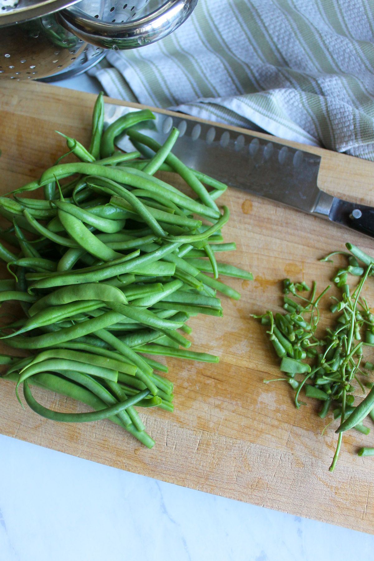 Raw green beans on a cutting board with the ends trimmed.