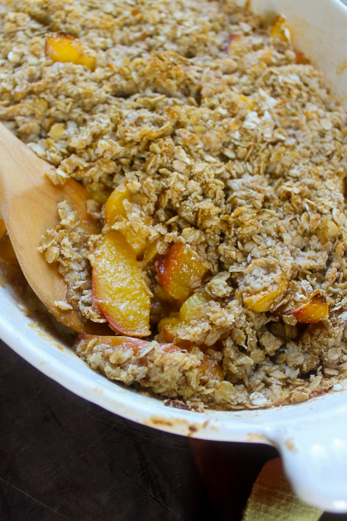 Baked peach crisp with a wooden spoon.