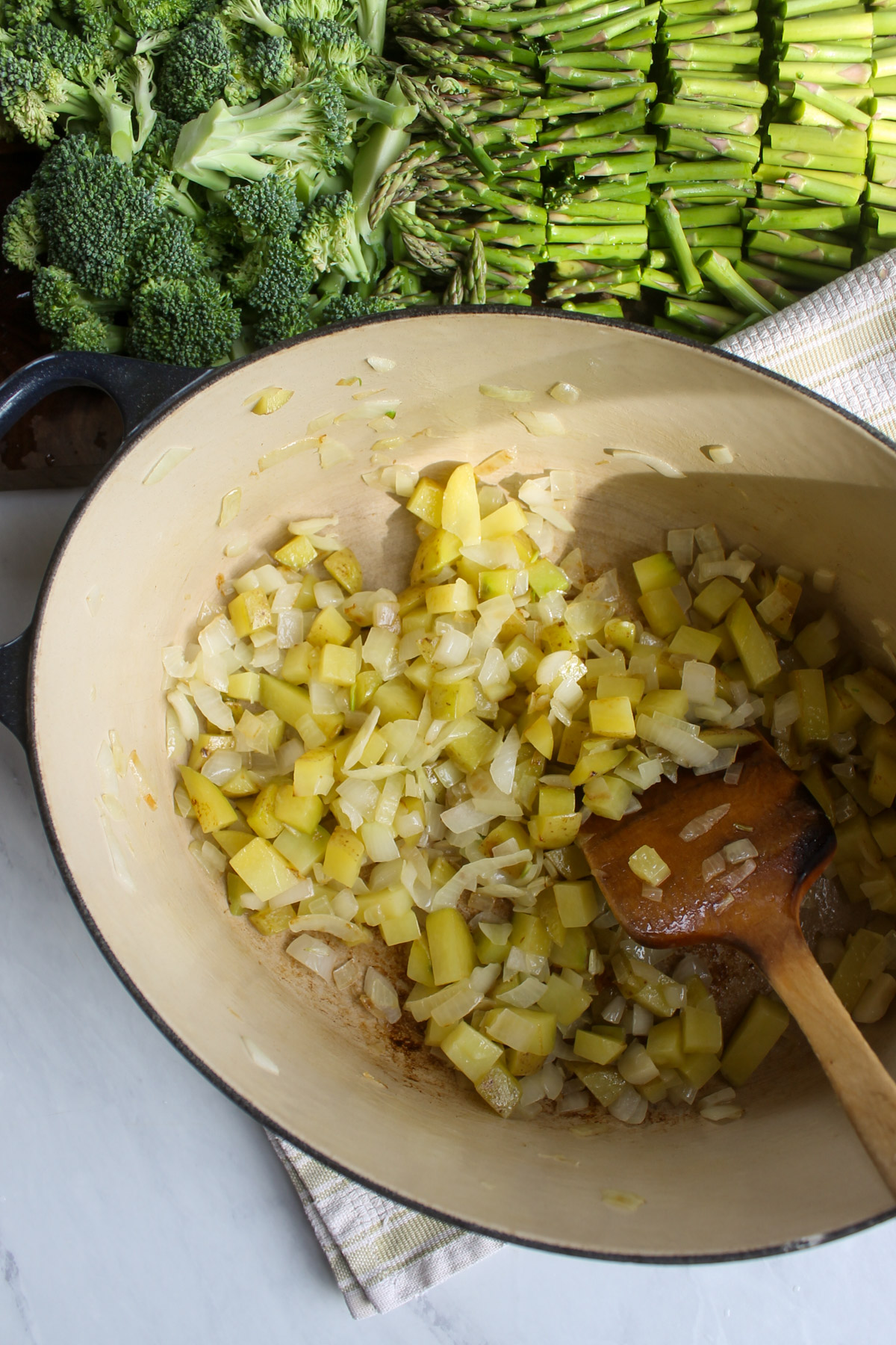 Onion and potato sauteing in a pot.